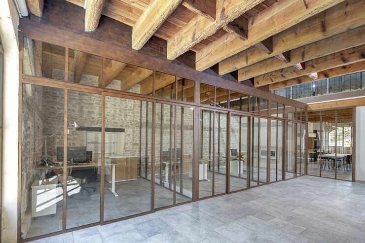 Une verrière en aluminium de couleur rouille dans une ancienne grange